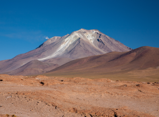 zaśnieżona góra pośród terenów z czerwoną ziemią