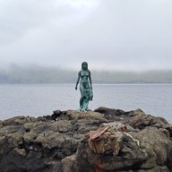sculpture of a naked woman on a rock cliff