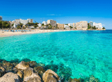 clear water and beach, with city buildings in the background