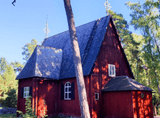 a small red wooden church in the forest