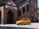 yellow Fiat 126p against the backdrop of a brick tenement building