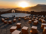 square seats at an amphitheatre, mountains and the rising sun in the background
