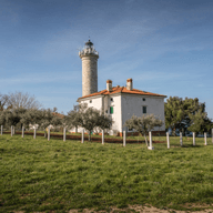 budynek latarni, kilka drzew i trawnik