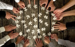 ręce układające puzzle na stole - getFindia