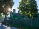 a green wooden mosque with a wooden fence in front