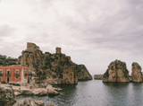 old tenement house by the bay, rocky hills in the background