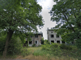two abandoned windowless buildings among trees