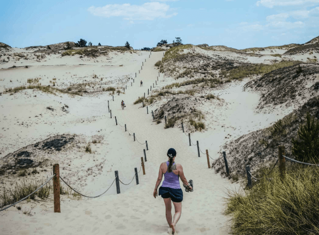 piaskowa góra, na którą wspina się kobieta