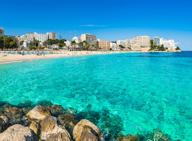 clear water and beach, with city buildings in the background