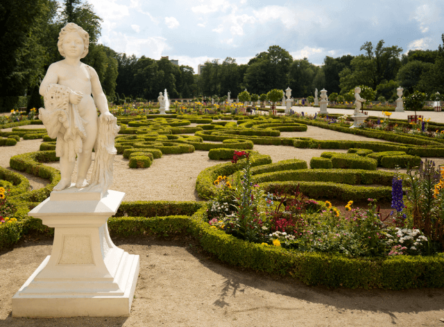 pomnik aniołka na piedestale, w tle francuski ogród